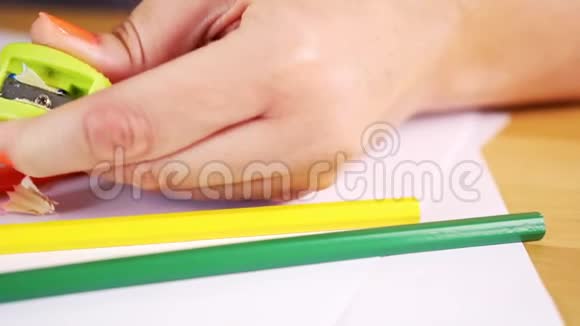 一个女人拿着一把卷笔刀和一支彩色铅笔在一张木桌上视频的预览图