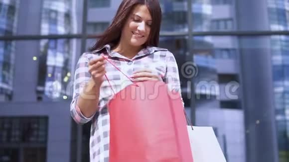 年轻女孩购物后打开包裹并对购买感到满意慢动作视频的预览图