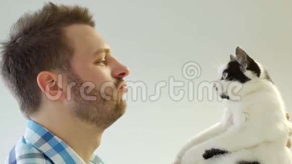 严肃时尚的年轻人留着胡须嗅着猫抚摸着猫特写白色背景视频的预览图