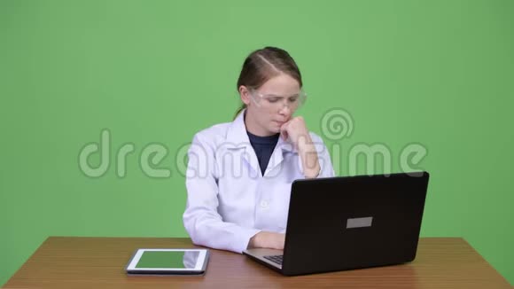 年轻快乐的女医生带防护眼镜带手提电脑和数码平板电脑视频的预览图