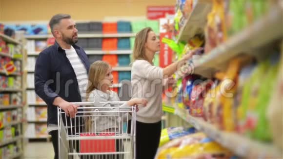 在超市三口幸福家庭手牵手走过商店的新鲜农产品部分父亲视频的预览图