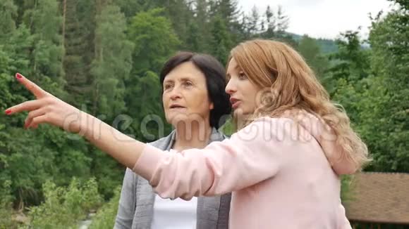 一位年迈的退休母亲和成年女儿正在树林茂密的山脉背景下交谈假期视频的预览图