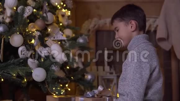 小男孩在圣诞树附近放了一个带礼物的盒子视频的预览图