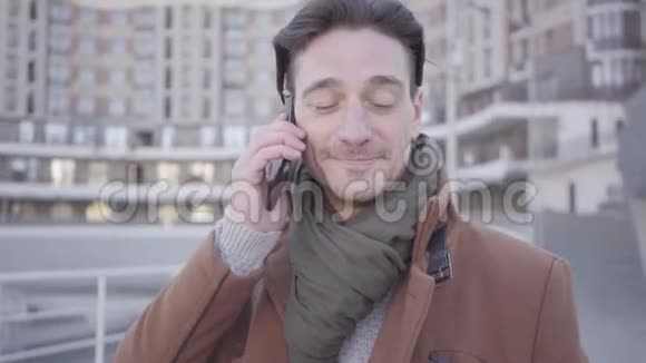 英俊的成功男人穿着棕色外套站在城市街道上用手机说话的肖像城市景观视频的预览图