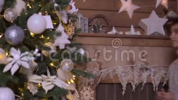 一个小男孩装饰一棵圣诞树一个漂亮的球心情很好视频的预览图