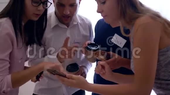 年轻的女孩和戴着徽章的男人拿着热咖啡的小面包在休息时间一起聊天视频的预览图