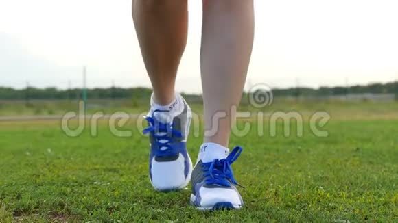 穿运动鞋的女孩在镜头方向的绿草上运动和户外娱乐活动视频的预览图