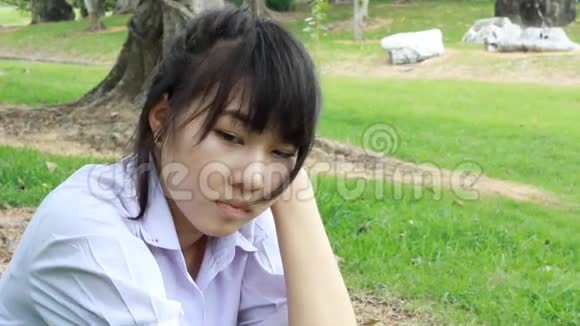 悲伤不快乐的泰国学生坐在公园里视频的预览图