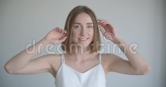在室内的白色房间里年轻漂亮的白种人女性在镜头前摆着发环的特写镜头视频的预览图