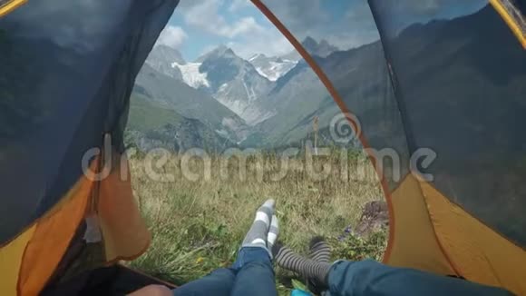 从山上的帐篷里看一对男女旅行者躺在帐篷里休息一下视频的预览图