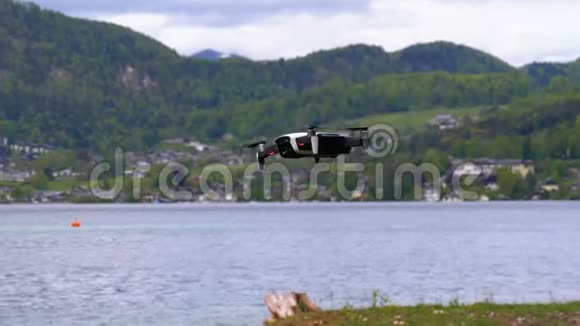 在湖和山的背景上悬挂旋转螺旋桨的钻头视频的预览图