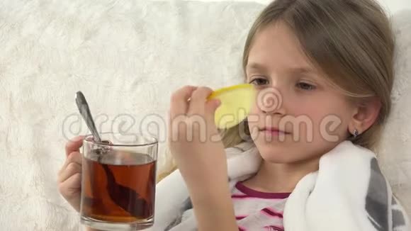 生病的儿童肖像喝柠檬茶悲伤的病女脸在床上沙发4K视频的预览图
