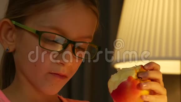 眼镜儿童肖像吃苹果女孩脸阅读晚上学习4K视频的预览图