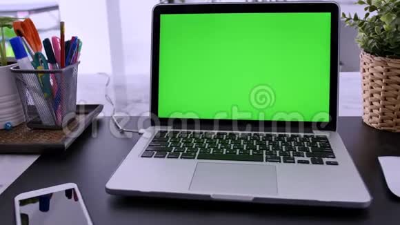 在客厅的办公桌上展示绿色彩色钥匙屏幕的笔记本电脑在背景舒适的客厅里多利动物园视频的预览图