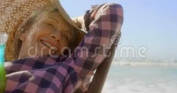 积极向上的高加索族女性在海滩4k的阳光休息室放松的前景视频的预览图