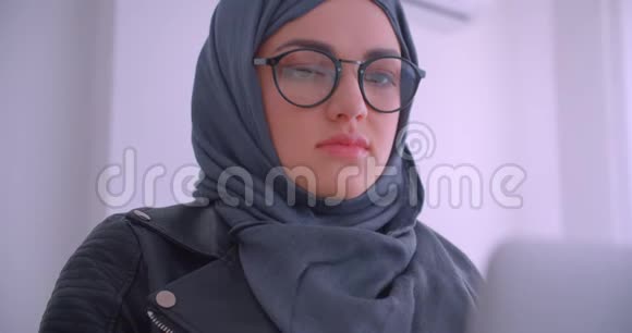 年轻迷人的穆斯林女商人戴着头巾的特写肖像戴着笔记本电脑看着相机的眼镜视频的预览图