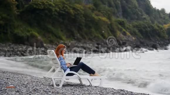 在海边的笔记本电脑上工作的女人视频的预览图