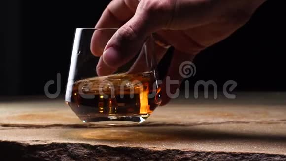 特写慢镜头手拿带威士忌的玻璃酒杯视频的预览图