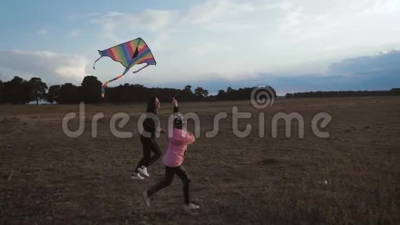 幸福的家庭母女在日落时分在草地上放风筝有趣的家庭时光友好家庭的概念视频的预览图