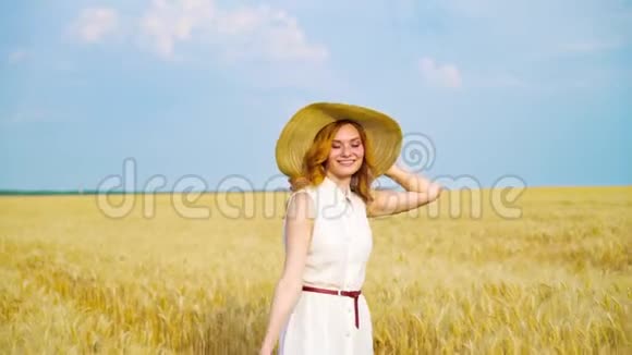 穿着白色衣服戴着草帽的年轻女子夏天在麦田里散步视频的预览图