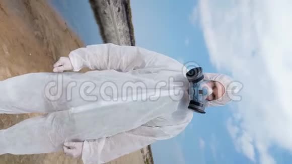 穿着防护服和呼吸器的人站在被污染的河流湖泊的塑料河岸上视频的预览图