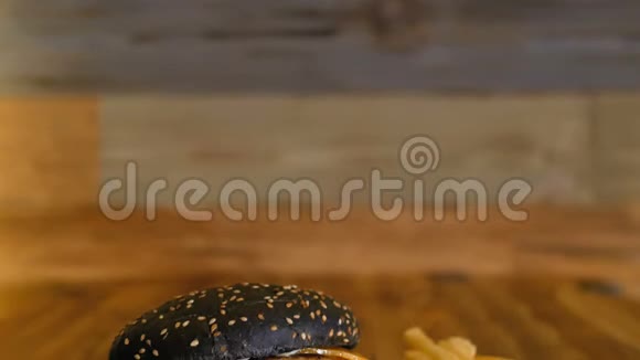 黑汉堡和大切片和蔬菜躺在一块木头上不健康的食物专业烹饪的快餐视频的预览图
