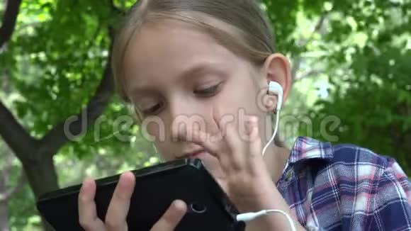 公园操场上玩平板电脑的孩子坐在长凳上的女孩4K智能手机视频的预览图