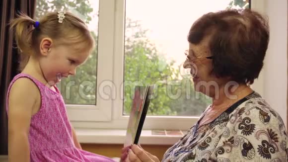 一个两岁的小女孩和她的祖母玩视频的预览图