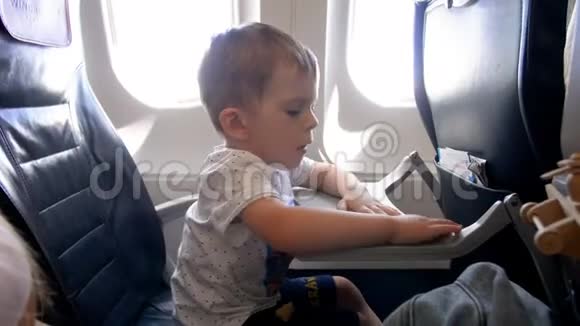 4k画面可爱的2岁小男孩坐在飞机的乘客座位上玩折叠桌视频的预览图