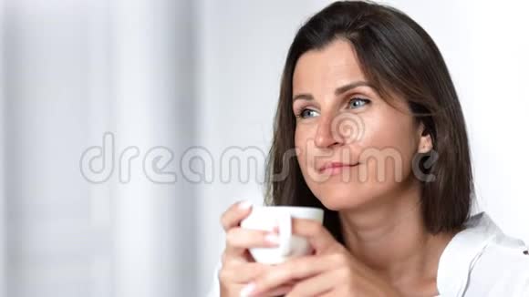 特写肖像满意的微笑妇女享受茶或咖啡室内拿着瓷杯视频的预览图