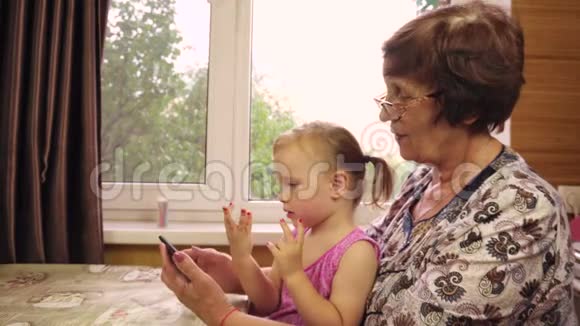一个两岁的小女孩和她的祖母玩视频的预览图