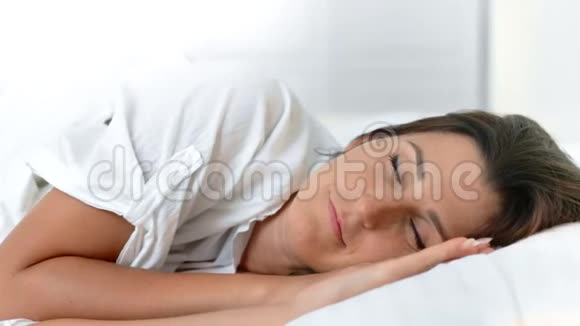 在舒适的白色床上醒来的清新微笑的女性肖像视频的预览图