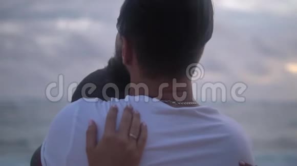 一对拥抱在海边的夫妇穿着白色t恤的男人轻轻地抱着他心爱的人视频的预览图