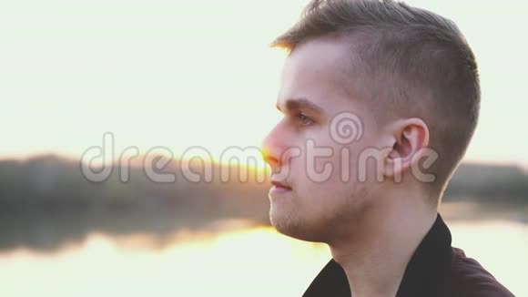 年轻英俊的男子戴着耳机在日落时在海滩上听音乐视频的预览图