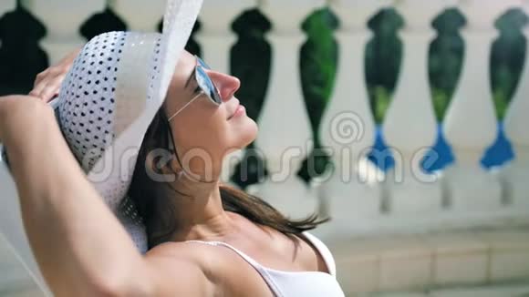 穿着泳衣在甲板椅上享受日光浴的放松女人举手视频的预览图