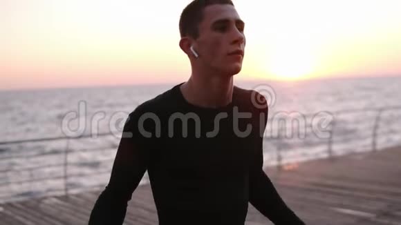 白人运动员穿着黑色运动服跳过户外跳绳阳光照在背景上海滨视频的预览图