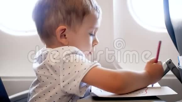 4k特写镜头可爱的2岁幼儿男孩在飞机上用彩色铅笔画画视频的预览图