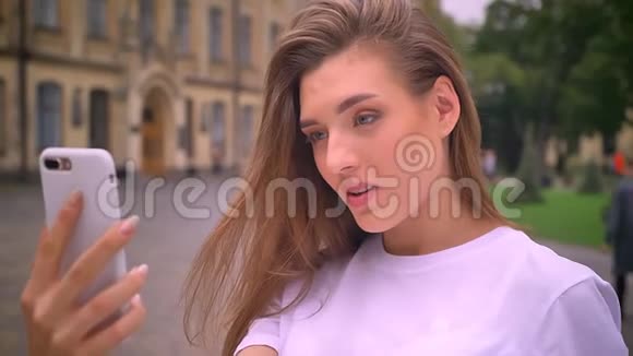 情感上令人敬畏的白种人女性正在大街上打视频电话在智能手机里谈笑风生白天视频的预览图