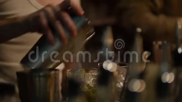 年轻的职业酒保把绿色饮料和冰块倒入杯子里视频的预览图