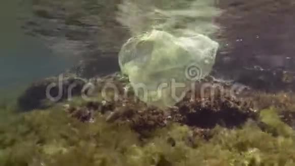 塑料污染沿海地区黄色塑料袋在美丽的礁石上丢弃的塑料袋表面有藻类视频的预览图