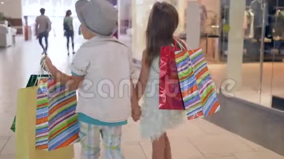 孩子们在购物时尚的儿童朋友在购物后通过购物中心的商店橱窗购物视频的预览图