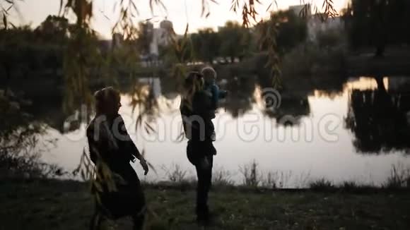 秋天公园湖背景上幸福家庭的剪影视频的预览图