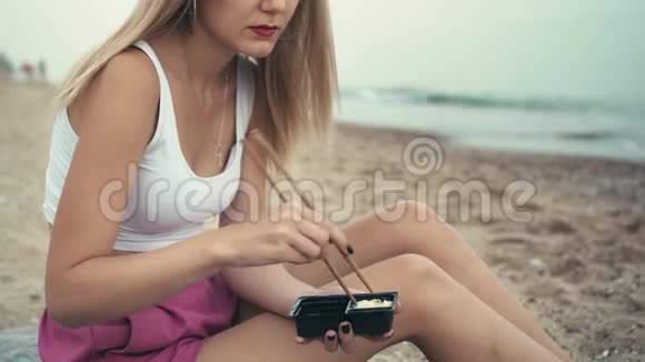 年轻的白种人无法辨认的女孩在海洋海岸吃寿司前用酱油搅动芥末沙子上的坑视频的预览图