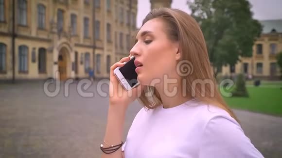 白种人女孩的手机对话她站在街上全神贯注地交谈视频的预览图