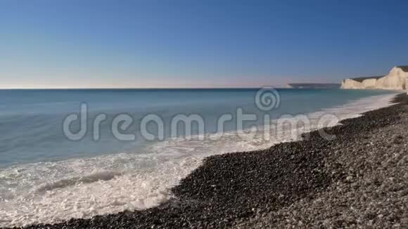 海浪撞击岩石海岸的日子在白垩悬崖背景下视频的预览图