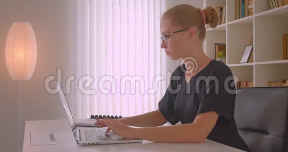 年轻貌美的高加索女商人戴着眼镜用笔记本电脑看着镜头开心地笑着视频的预览图