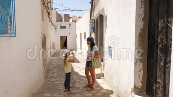 旅游女孩在狭窄的街道上喝着瓶子里的水在老城区散步视频的预览图