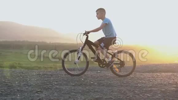 89岁的男孩穿着蓝色T恤在日落或日出时骑着黑色自行车在山区视频的预览图