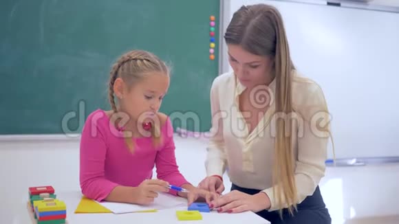辅导女教育家帮助学者女孩获得信息使用塑料数字在黑板附近的桌子视频的预览图