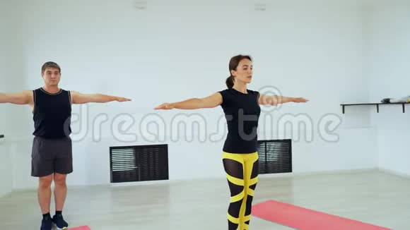 一个男人有两个女孩站在一条腿上手臂伸到两边一群人在做普拉提视频的预览图